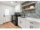 Modern laundry room with black washer/dryer, white cabinets, and stylish herringbone backsplash at 7802 E Hubbell St, Scottsdale, AZ 85257