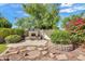Charming backyard with an outdoor fireplace, decorative stone pavers, and beautiful landscaping at 8009 W Salter Dr, Peoria, AZ 85382