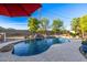 Sparkling swimming pool with rock features and lush landscaping in a private backyard setting at 8132 W Hatfield Rd, Peoria, AZ 85383