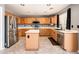 Well-lit kitchen featuring stainless steel appliances, a functional island, and wood cabinets offering ample storage space at 9735 W Kirby Ave, Tolleson, AZ 85353