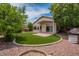 Well-manicured backyard featuring artificial grass, mature trees, and a quaint patio area at 10722 W Irma Ln, Peoria, AZ 85373