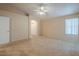 Large bedroom with neutral carpet, ceiling fan, and a door leading to another room at 10722 W Irma Ln, Peoria, AZ 85373