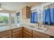 Bright kitchen featuring a double basin sink, updated faucet fixtures, and natural light from three windows at 10722 W Irma Ln, Peoria, AZ 85373