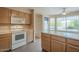 Kitchen with white appliances, wood cabinetry, tile flooring, and a breakfast bar area illuminated by natural light at 10722 W Irma Ln, Peoria, AZ 85373