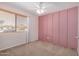 Bright bedroom with carpet, ceiling fan, window, and a pink accent wall offers a comfortable and stylish retreat at 11531 E Persimmon Ave, Mesa, AZ 85212