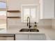 Bright kitchen features a stainless steel sink, open shelving, and a window for ample natural light and modern charm at 11531 E Persimmon Ave, Mesa, AZ 85212