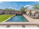 Inviting rectangular pool with travertine tile, waterfall feature, and lounge chairs for relaxation at 12712 W Milton Dr, Peoria, AZ 85383