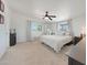 Spacious bedroom with large window, neutral carpet, ceiling fan, and dark wood furniture at 12810 N 20Th St, Phoenix, AZ 85022