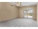 Neutral living room boasting plush carpet, ceiling fan, and sliding door to backyard at 13861 W Elm St, Surprise, AZ 85374