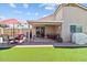 Backyard featuring artificial turf, patio area with red umbrella and covered seating at 16538 N Oachs Dr, Surprise, AZ 85374