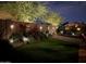 Beautiful backyard featuring artificial grass, brick walls, beautiful landscaping, and soft lighting at night at 16538 N Oachs Dr, Surprise, AZ 85374
