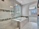 A luxurious bathroom boasting a sleek soaking tub, neutral tile accents, and a glass shower at 16881 W Merrell St, Goodyear, AZ 85395