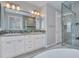 A luxurious bathroom with double vanity, a large mirror, glass shower and neutral tile accents at 16881 W Merrell St, Goodyear, AZ 85395