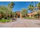 Beautiful walkway leading to an arched entryway of a tan home, surrounded by lush trees at 16881 W Merrell St, Goodyear, AZ 85395