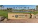 The entrance to PebbleCreek Model Home Village features a pond, trees, and a lit sign at 16881 W Merrell St, Goodyear, AZ 85395