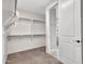 Spacious walk-in closet with neutral carpet and view to luxurious bathroom for convenience at 16881 W Merrell St, Goodyear, AZ 85395
