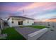 Beautiful backyard with artificial grass, paver patio, and pristine white exterior walls at sunset at 24047 W Cocopah St, Buckeye, AZ 85326