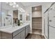 Well-lit bathroom featuring dual sinks, sleek gray cabinets, and a glass shower enclosure with tiled flooring at 24047 W Cocopah St, Buckeye, AZ 85326