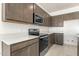 Modern kitchen with stainless steel appliances, quartz countertops and stylish brown cabinets at 24047 W Cocopah St, Buckeye, AZ 85326