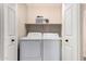 Functional laundry area with modern washer, dryer, storage shelf, and convenient access at 29161 N Lilly Ln, San Tan Valley, AZ 85143