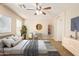 Staged main bedroom features a ceiling fan, wood-look floors, and a comfortable chair at 29161 N Lilly Ln, San Tan Valley, AZ 85143