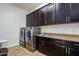 Functional laundry room equipped with dark cabinetry, modern appliances, and granite countertops at 35443 N 87Th Pl, Scottsdale, AZ 85266