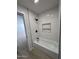 Modern bathroom with white tiled shower, black fixtures, and convenient built-in shelving at 3933 E Flower St, Phoenix, AZ 85018