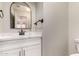 Powder room features modern fixtures, white vanity, and arched mirror at 408 E Silverwood Dr, Phoenix, AZ 85048