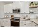 Kitchen with white cabinets, tile backsplash, stainless steel appliances and quartz countertops at 42440 W Peters Dr, Maricopa, AZ 85138
