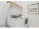 Bright laundry room with front load washer/dryer, white cabinets and decorative wall art at 42440 W Peters Dr, Maricopa, AZ 85138