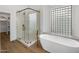 Modern bathroom with glass-enclosed shower, soaking tub, and a light-filled glass block window at 5520 E Muriel Dr, Scottsdale, AZ 85254