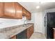 This kitchen features wood cabinets, stainless steel sink, black dishwasher and refrigerator at 8125 N 32Nd Dr, Phoenix, AZ 85051