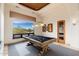Bright game room boasts a billiard table, custom lighting, artwork, and large window with views of the backyard at 10267 E Cinder Cone Trl, Scottsdale, AZ 85262