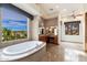 Large main bathroom offers tub with scenic views, double sinks, and decorative lighting fixtures at 10267 E Cinder Cone Trl, Scottsdale, AZ 85262