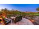 Inviting outdoor patio with green seating, wrought iron trim, desert views, and beautiful brick pavers at 10267 E Cinder Cone Trl, Scottsdale, AZ 85262