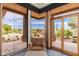 Bright sun room offers desert views through large windows, featuring stylish seating and outdoor access at 10267 E Cinder Cone Trl, Scottsdale, AZ 85262