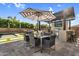 Backyard view of the complete outdoor kitchen featuring a grill, bar seating, and an umbrella at 10353 E Trillium Ave, Mesa, AZ 85212
