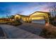 Home featuring desert landscaping, pavers, and a three-car garage under a vibrant sky at 11385 N Luckenbach St, Surprise, AZ 85388