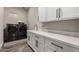 Laundry room with white cabinetry, countertops, modern washer and dryer, and gray accents at 11385 N Luckenbach St, Surprise, AZ 85388