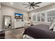 Bright main bedroom featuring wood floors, a ceiling fan, plantation shutters and seating area at 11385 N Luckenbach St, Surprise, AZ 85388