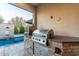 Outdoor kitchen area featuring a built-in grill, pizza oven, and stone counter, next to the pool at 11385 N Luckenbach St, Surprise, AZ 85388