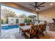 Covered patio with dining set, grill, pizza oven, and view of pool and landscaping at 11385 N Luckenbach St, Surprise, AZ 85388
