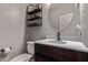 This bathroom features a dark brown vanity, toilet, modern lighting, and round mirror at 12226 W Planada Ln, Sun City, AZ 85373