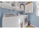 Well-equipped laundry room with modern washer and dryer, storage shelves, and natural light at 15241 W Madison St, Goodyear, AZ 85338