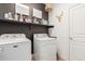 Functional laundry room with modern washer and dryer units and wall shelving at 15488 W Aster Dr, Surprise, AZ 85379