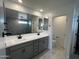 Modern bathroom featuring a double vanity, large mirror, and marble-look floors and shower in this home at 17481 W Fulton St, Goodyear, AZ 85338