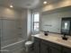 Bathroom featuring a double sink vanity, large mirror, and tub with shower at 17481 W Fulton St, Goodyear, AZ 85338