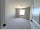 Bright bedroom featuring neutral walls, new carpet, and a large window at 17505 W Fulton St, Goodyear, AZ 85338