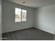 Cozy bedroom with neutral carpet, white walls, and a window overlooking the neighborhood at 17511 W Fulton St, Goodyear, AZ 85338