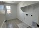 This bright laundry room has tile floors, a utility sink connection, and open shelving at 17511 W Fulton St, Goodyear, AZ 85338